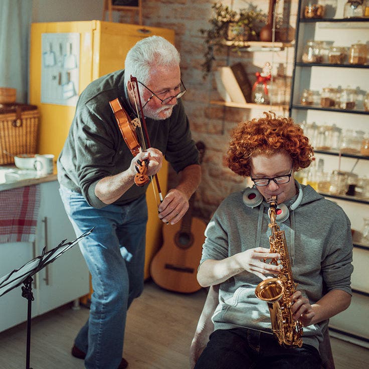 Grandfather and grandson jamming with musical instruments in the kitchen