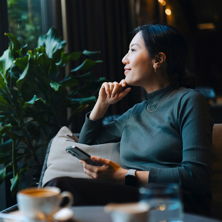 Woman in green jumper, sitting in a cafe and looking out the window