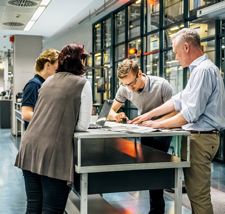 Four people standing around work table in office