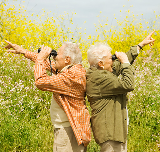 An elderly couple  watching in binoculars
