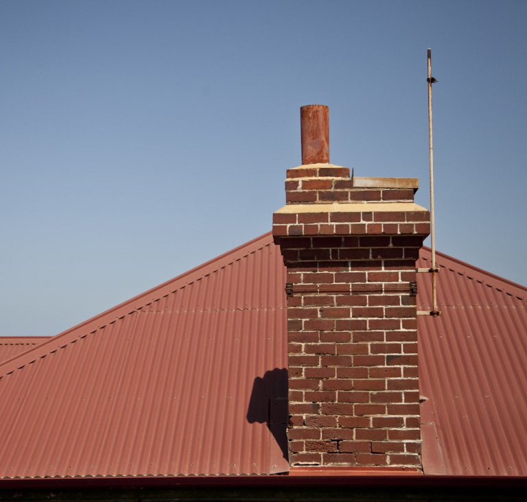 Close up of clay coloured tiled roof with chimney