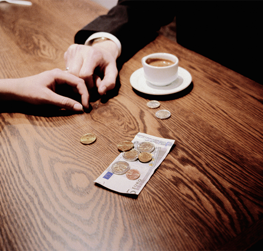 couple's hand, coffee, and bills in the table