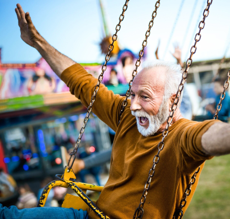 Man sitting in carnival ride swing with arms outstretched