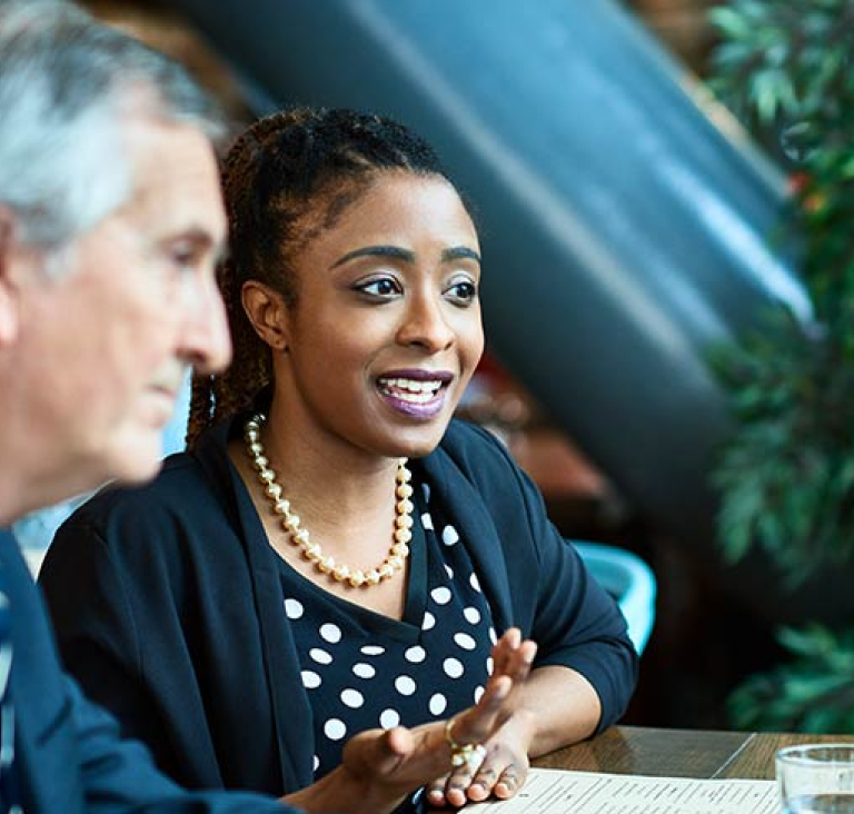 Woman sitting at desk speaking with older man
