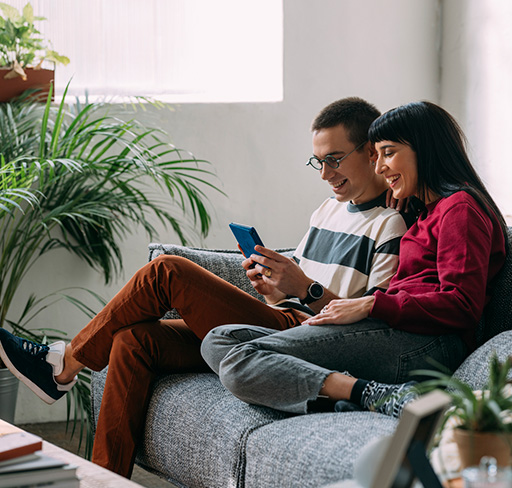 Couple sitting in sofa watching mobile