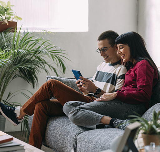 couple watching phone sitting on sofa