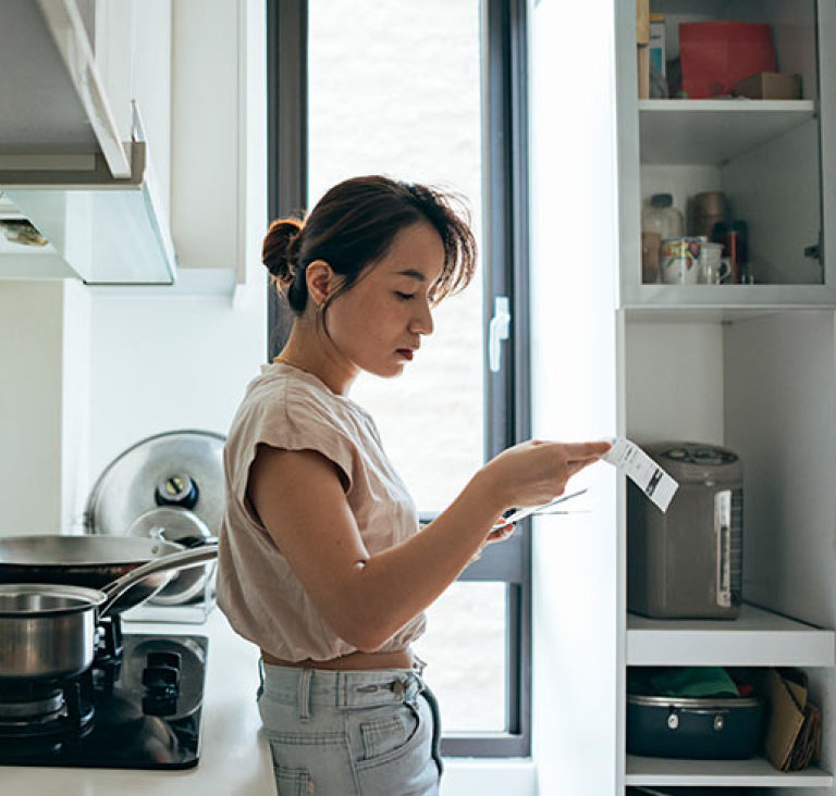 Woman leaning against stove top reading letter