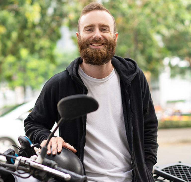 Man standing on road by motorbike