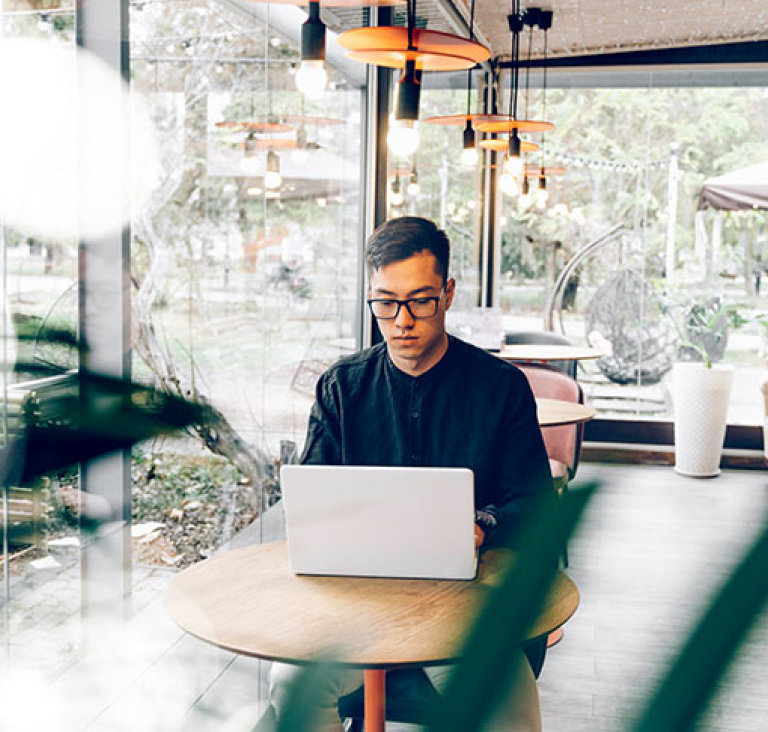 Man typing on laptop while sitting at round table in office
