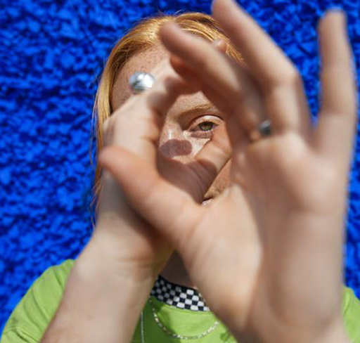 A woman framing a face using hands on a blue background