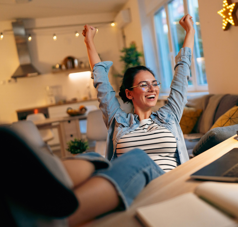 Woman with arms in air sitting at desk