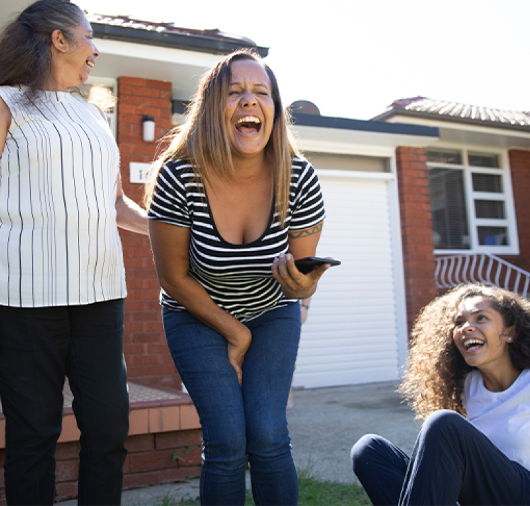Women smiling and laughing in front of house