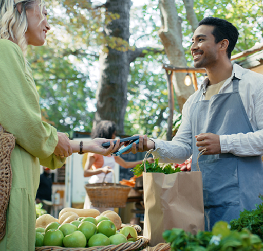 Contactless payment at an outdoor farmers market stall with fresh green apples
