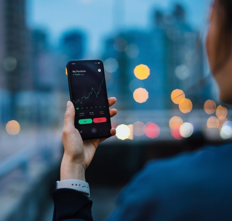Close up of woman's hand holding phone, cityscape in background