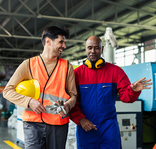 Two workers walking and discussing inside a factory