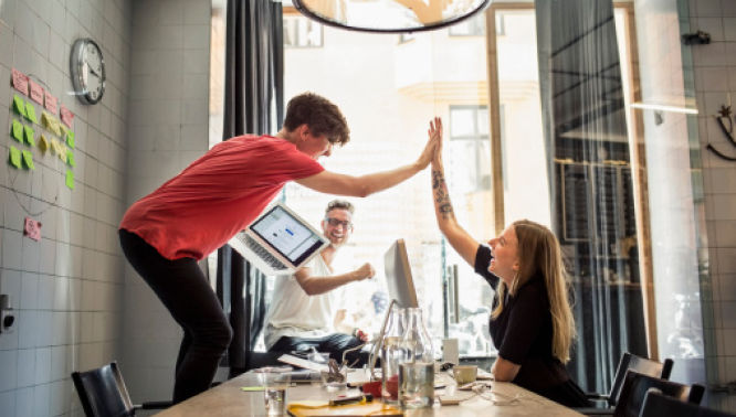 Two person high five while working in office
