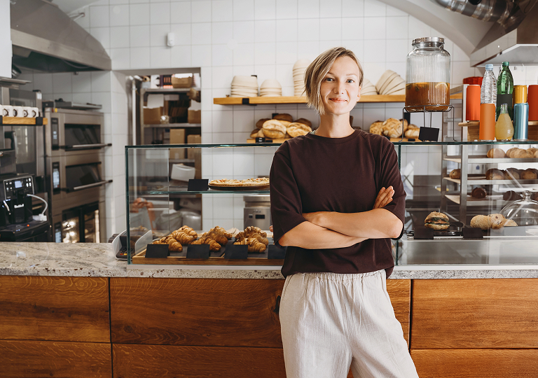 Woman standing in cafe, arms crossed