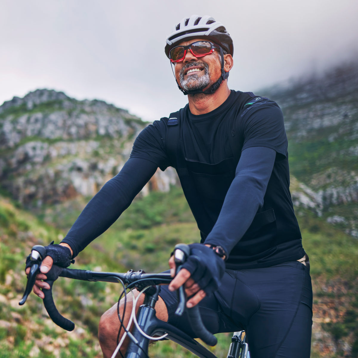 Man sitting on a bicycle, wearing a helmet and smiling