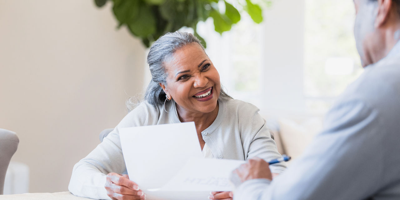 Elderly woman smiling while holding a piece of paper