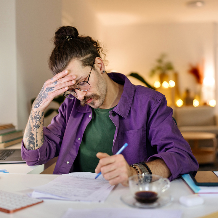 Man in purple shirt stresses over paperwork