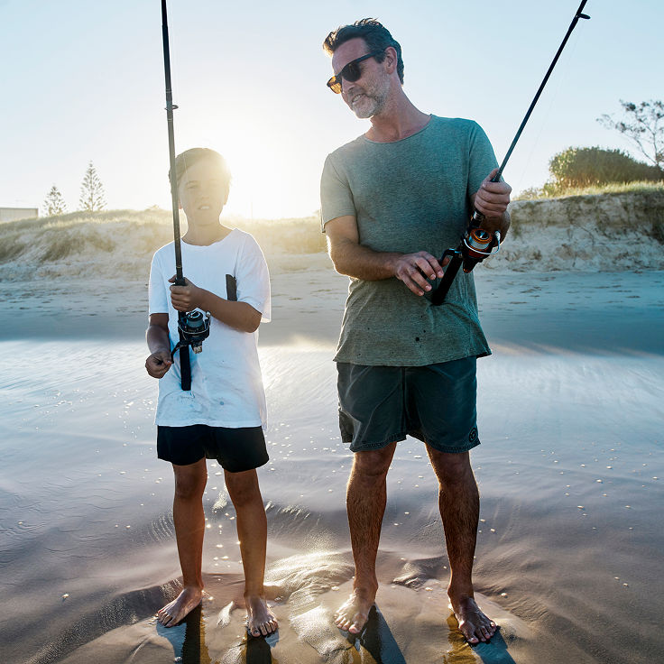 Father and son fishing on beach