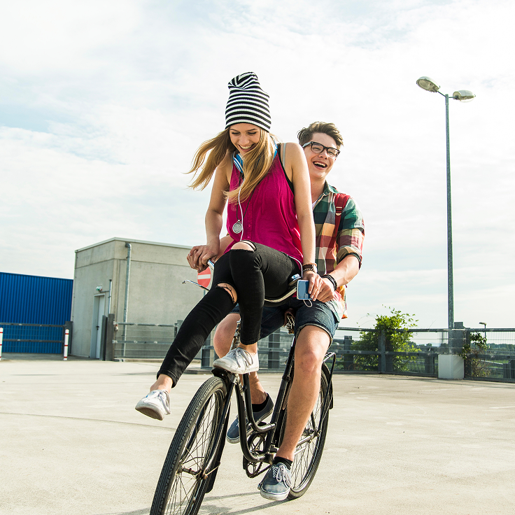 Girl sitting on front of bike that boy is riding