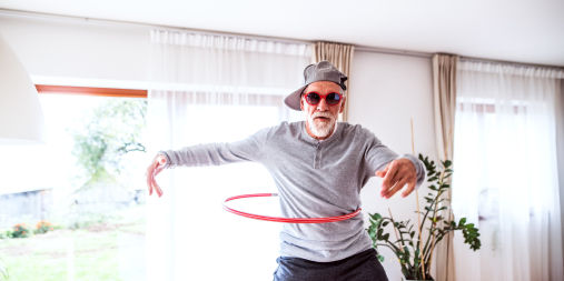 Older man hula hooping in living room