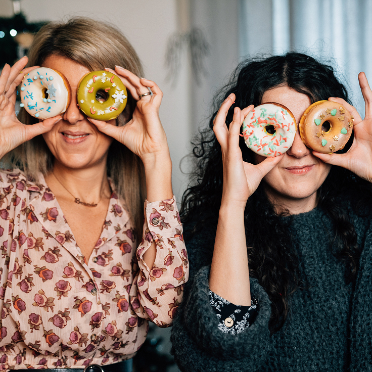Two women holding donuts over their eyes