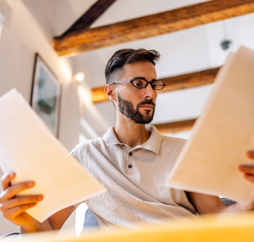 Person reviews paperwork at home, comparing documents to check details and responsibilities.