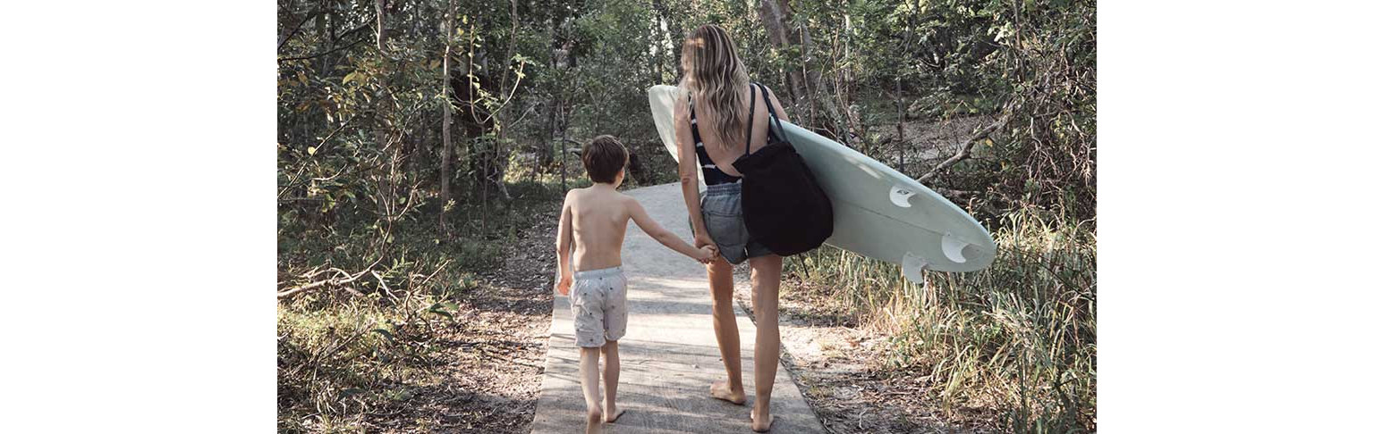 Woman and boy walking with surfboard