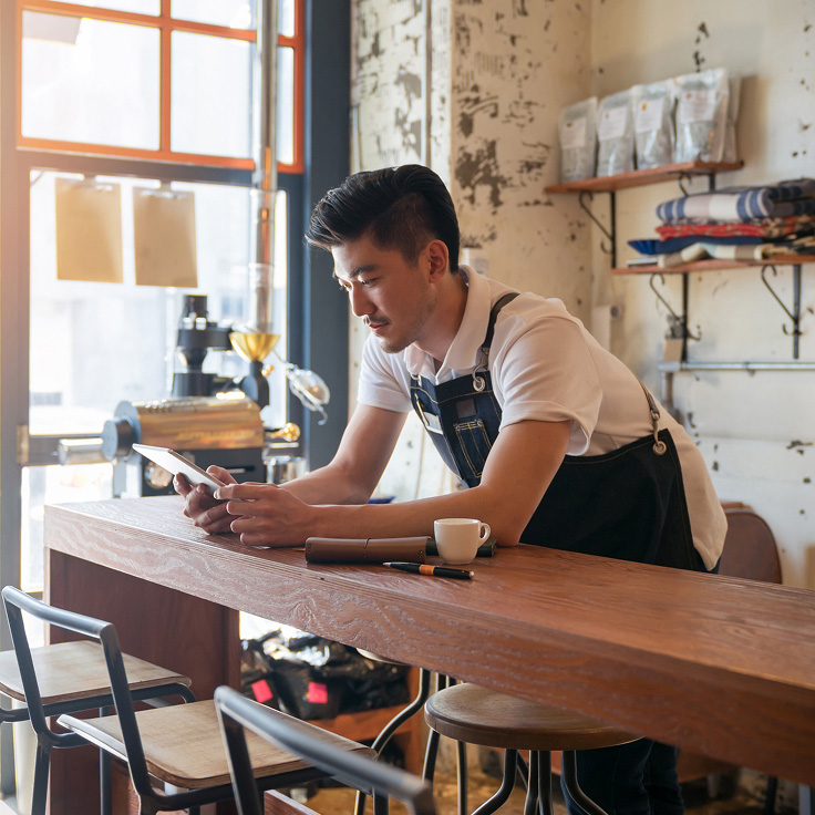 Man working in cafe, looking at phone