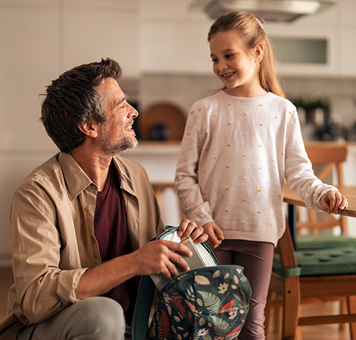 A father and daughter smiling and looking at each other indoors