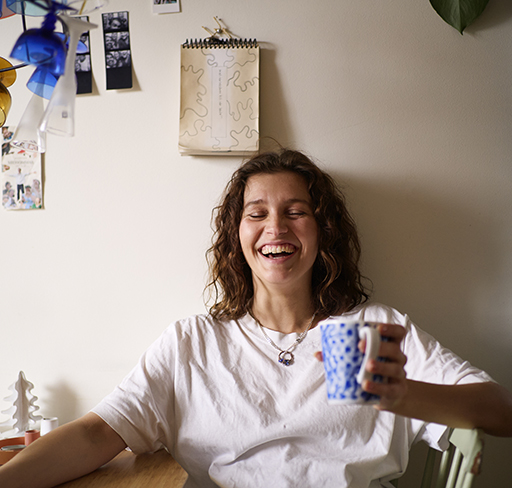 A woman holding a coffee mug and laughing
