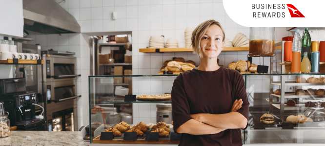 Woman standing in bakery, smiling with arms crossed