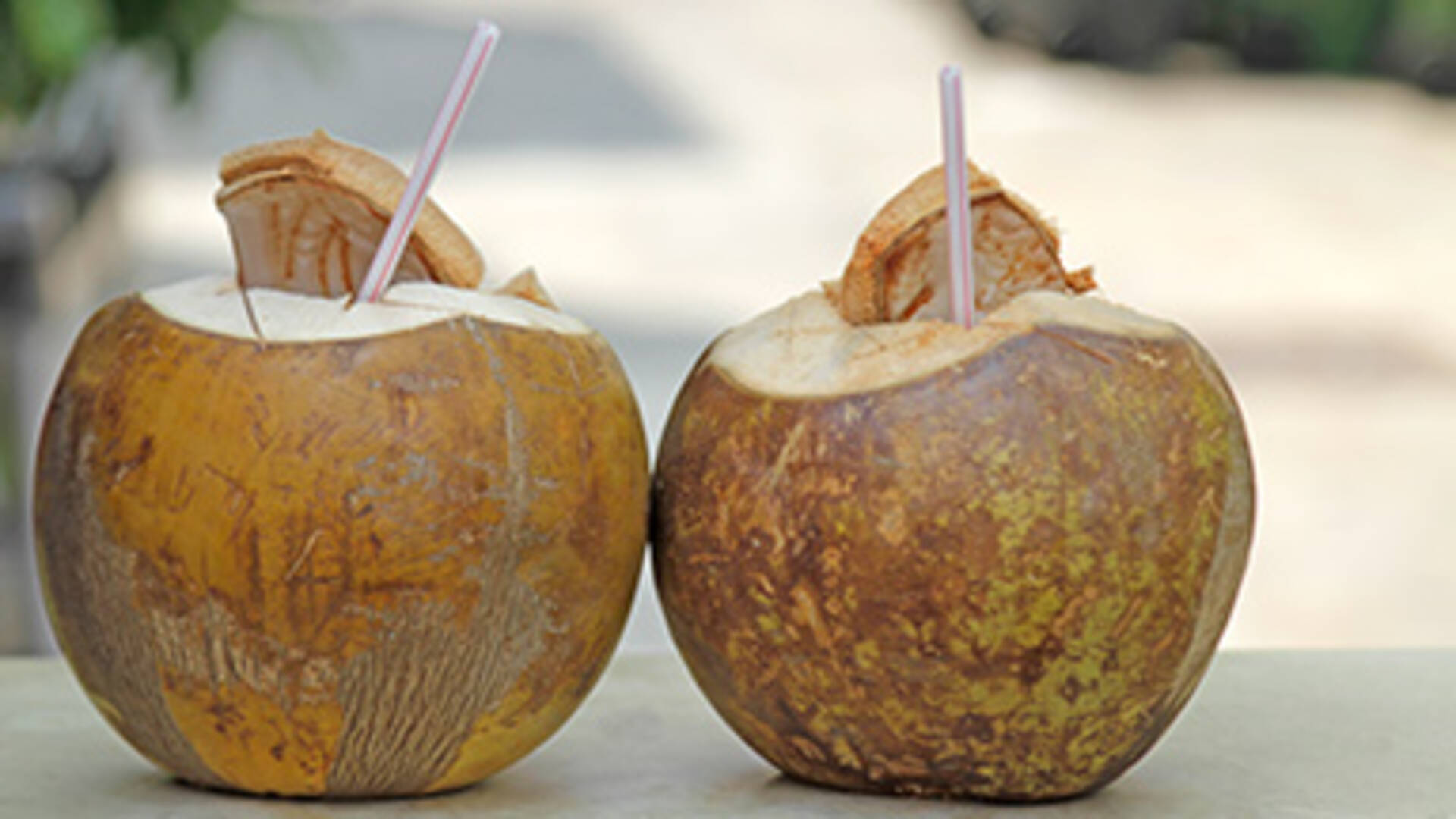 Two tender coconuts with straw inside