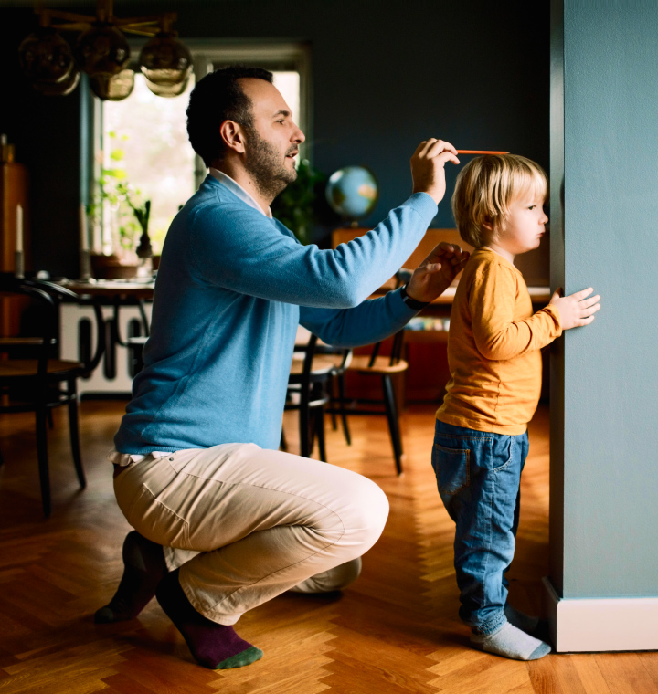 Father measures childs height against doorframe