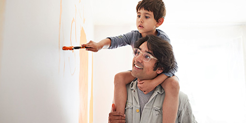 Father holding son to paint the wall