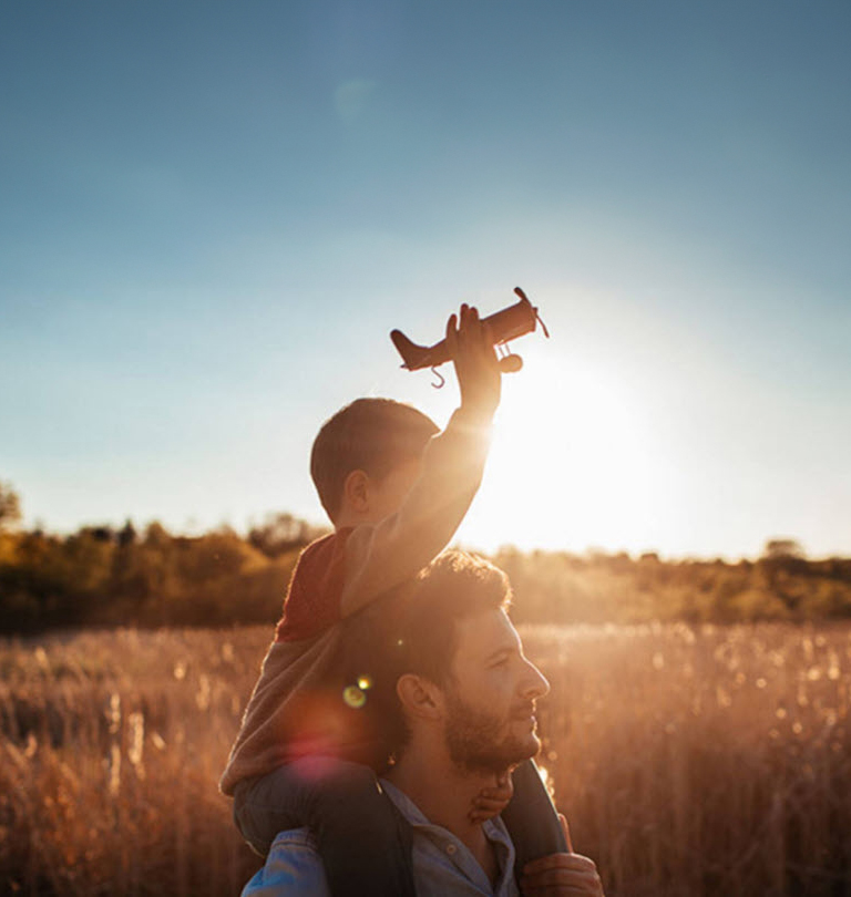 Father carrying son with toy plane