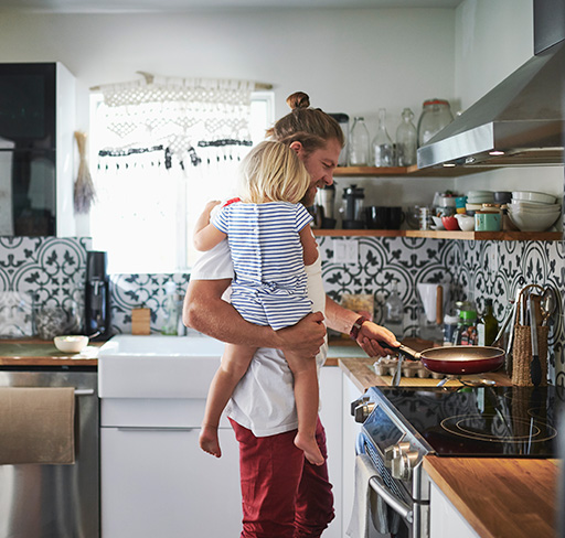 Father carrying child and cooking