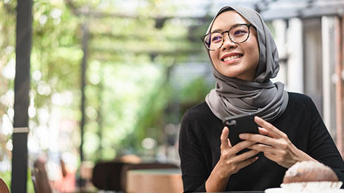 Woman sitting outdoors, smiling, holding phone
