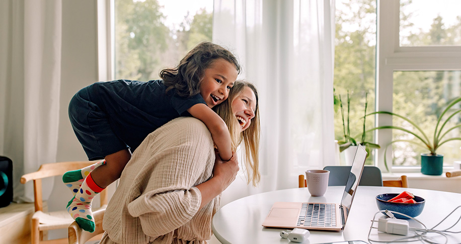 Mum working from home with daughter laughing