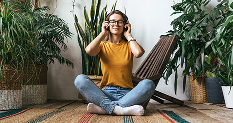 woman surroudned by indoor plants listening to music
