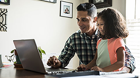 Dad and daughter watching laptop